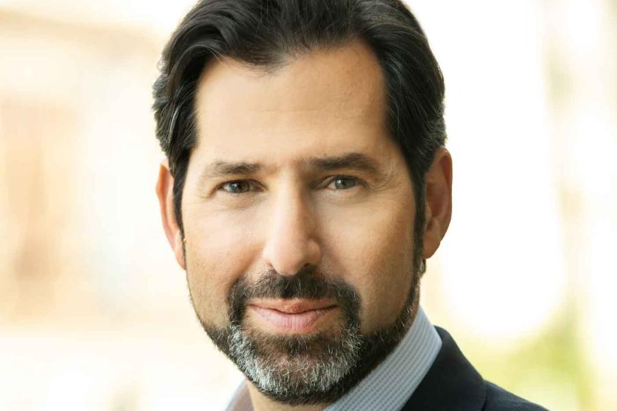 A headshot of David Folkenflik, with black short hair and a salt and pepper beard and mustache, wearing a suite jacket.