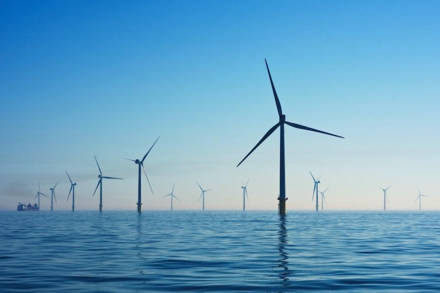 Wind turbines in calm water against a blue dusk sky