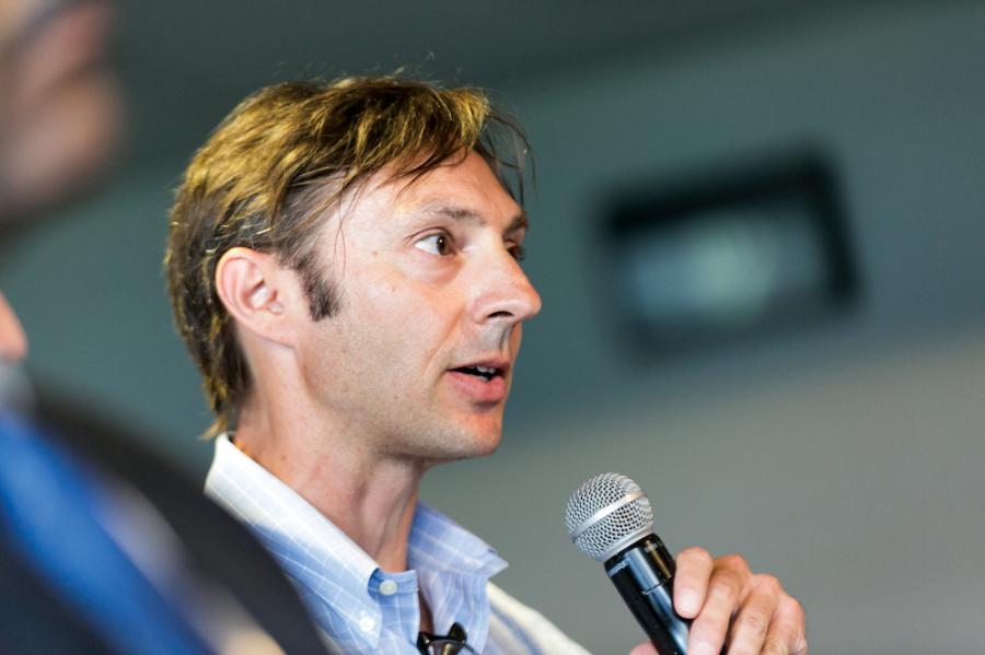 Person speaking into a microphone, looking thoughtful