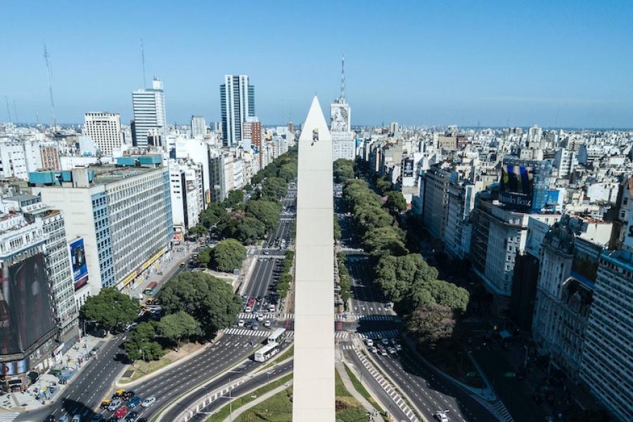 Light-colored stone oblisk with a city in the background