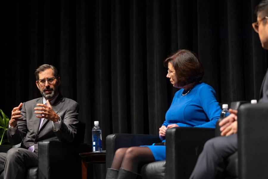 Three people sitting in chairs on a stage
