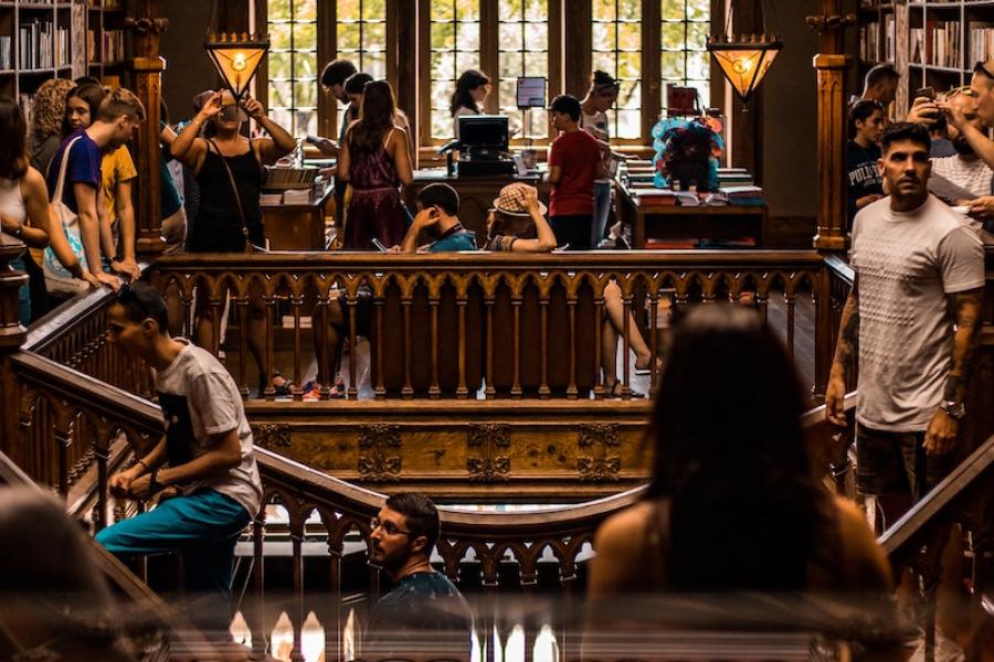 Library room with tall, ornate windows, crowded with people