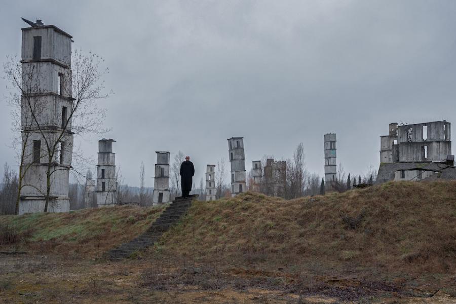 Film still showing a person standing among white towers in a bleak landscape