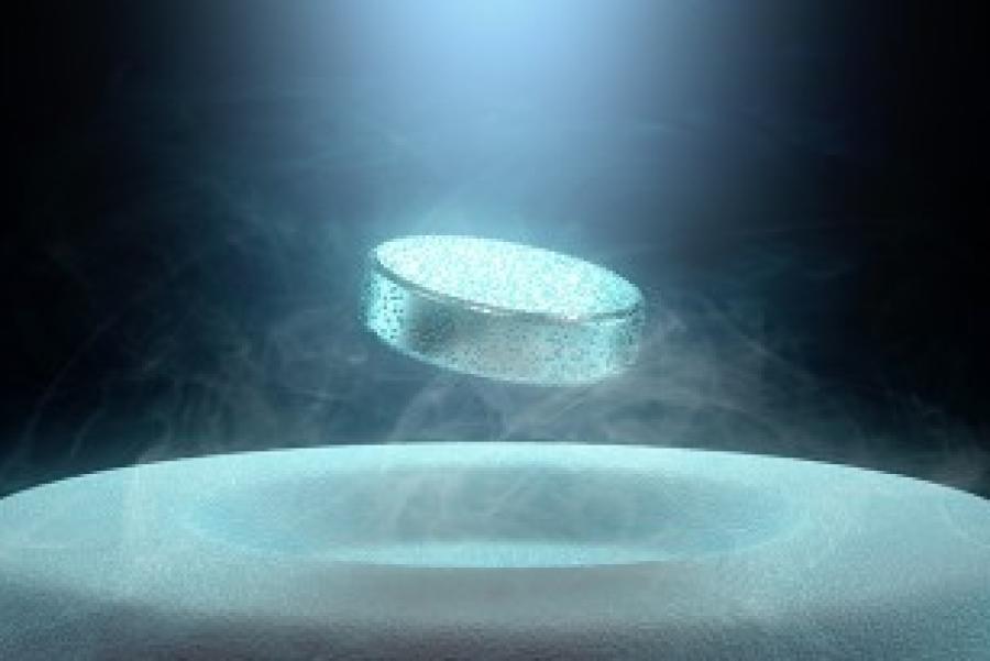 metal puck levitates above a slightly pitted white surface