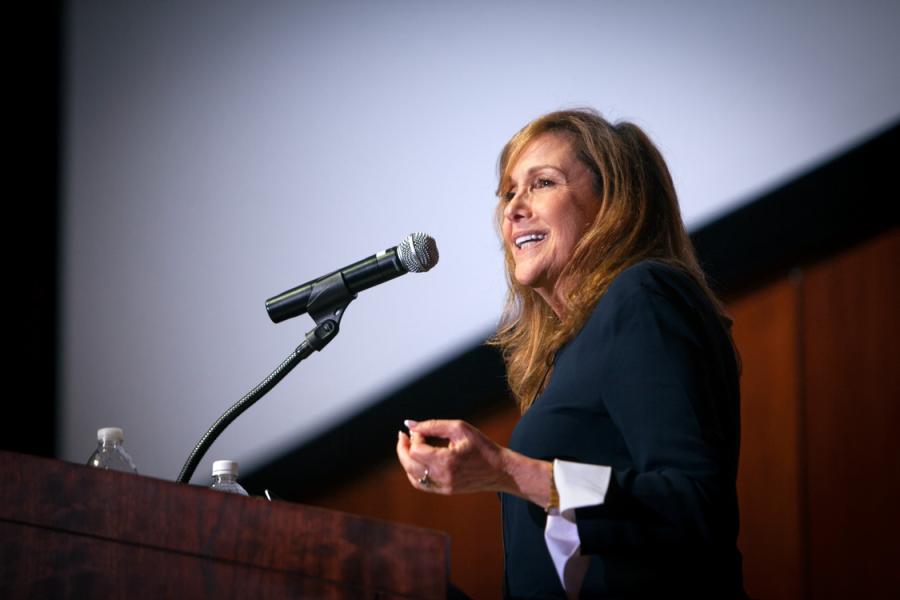 Person standing at a podium, smiling and gesturing