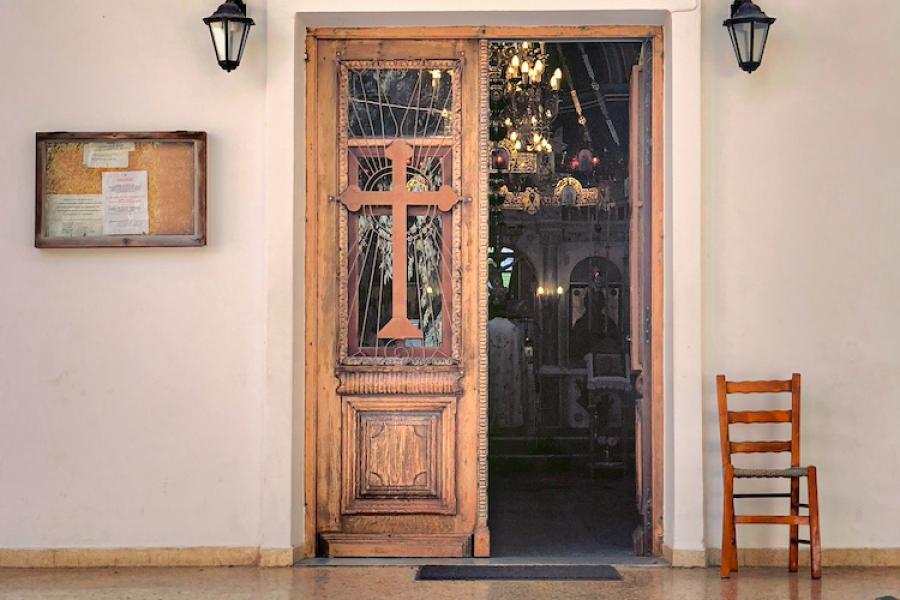 Doorway decorated with a wooden cross and colorful painting of four figures