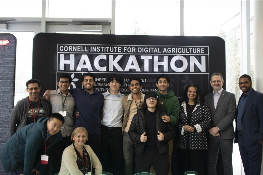 Several people pose in front of a sign that says "HACKATHON"