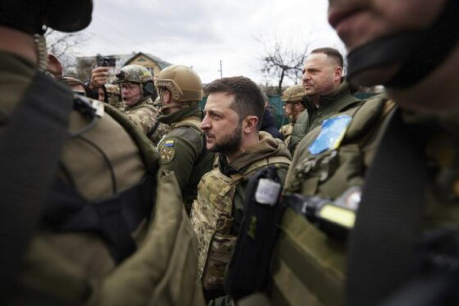 Several people in army fatigues surround a man, the leader, with a beard