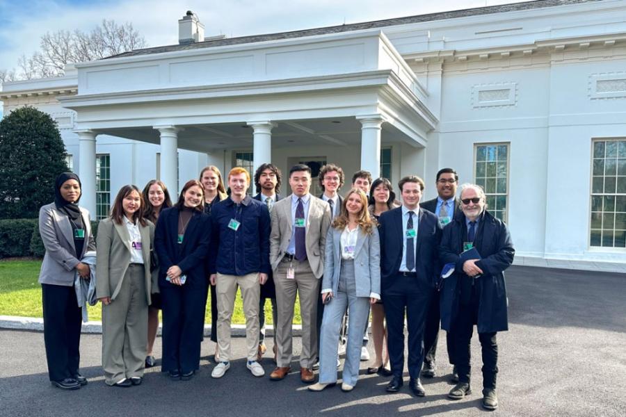 Several people stand in front of a white portico