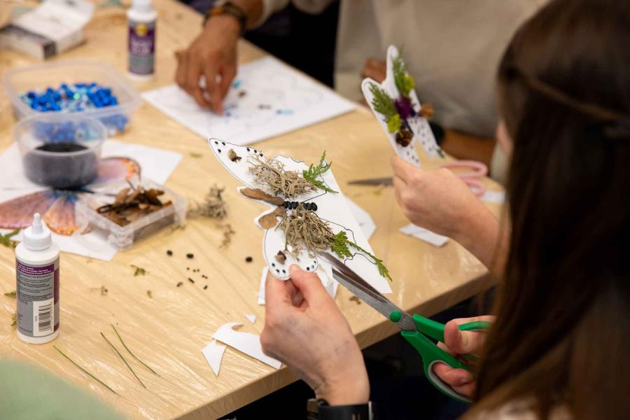 person creating a butterfly from paper and natural objects