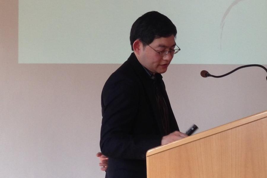 Person speaking at a podium with a slide projected behind