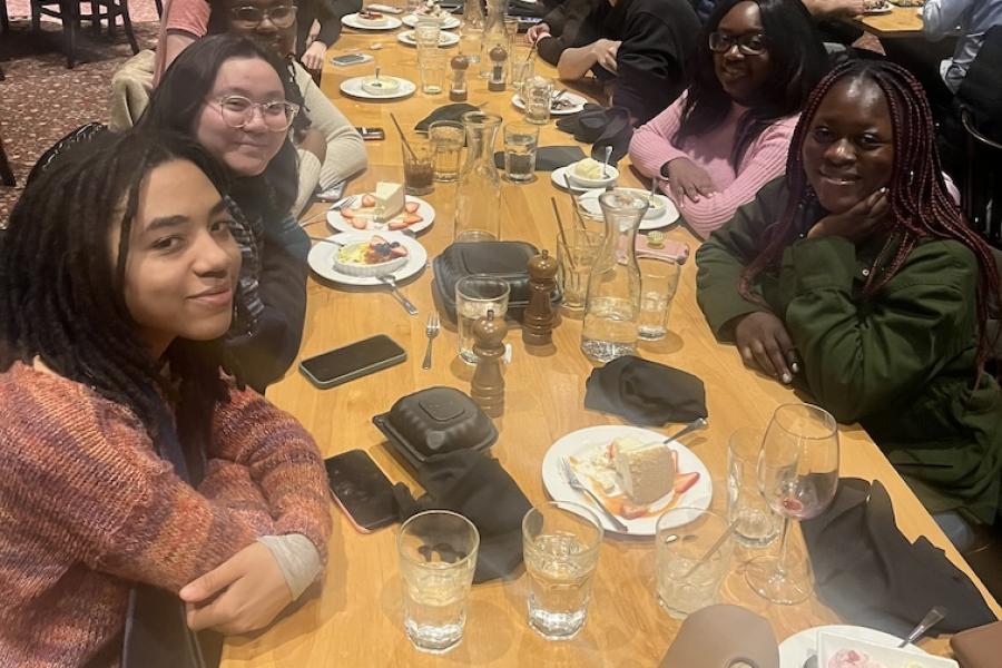 Students sit at table in restaurant under bright lights.
