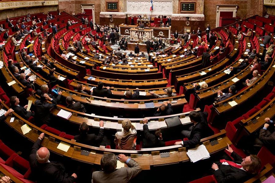 Inside a legistative chamber, seats circling a central podium
