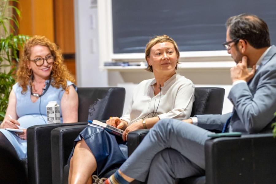 Three people sit in armchairs, part of a panel discussion event