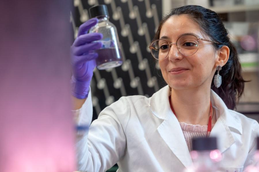 Person in lab coat holding a glass bottle