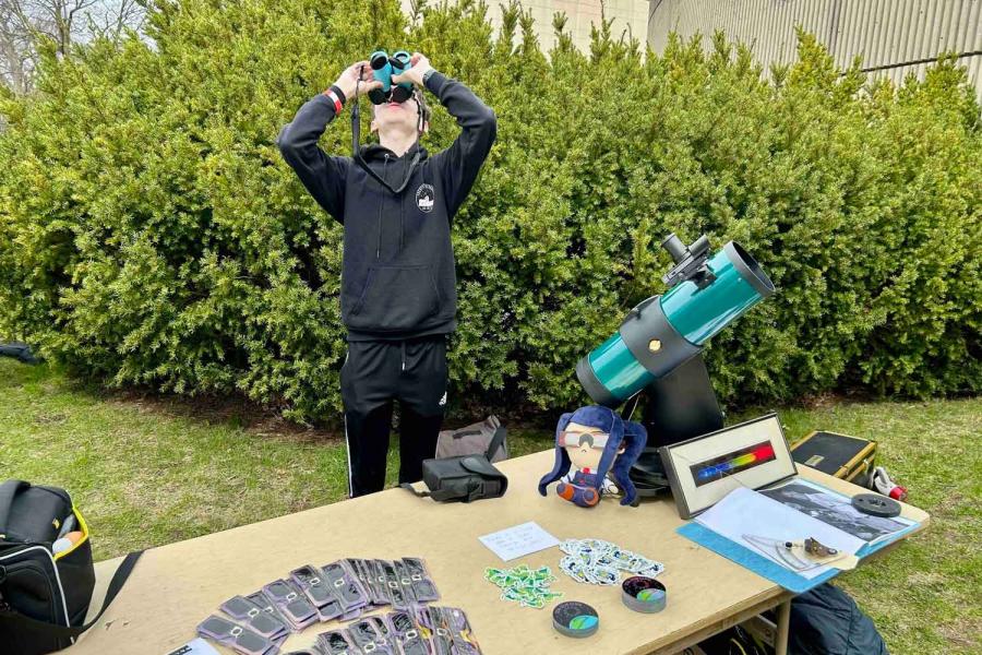 person looking through binoculars at the sky