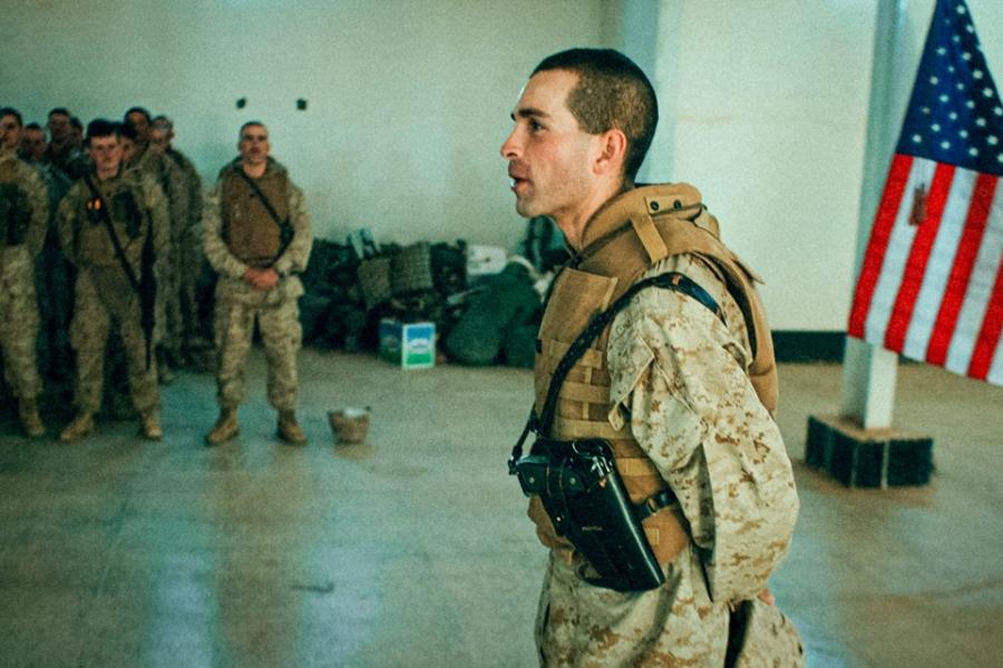 Person in military fatigues addresses others