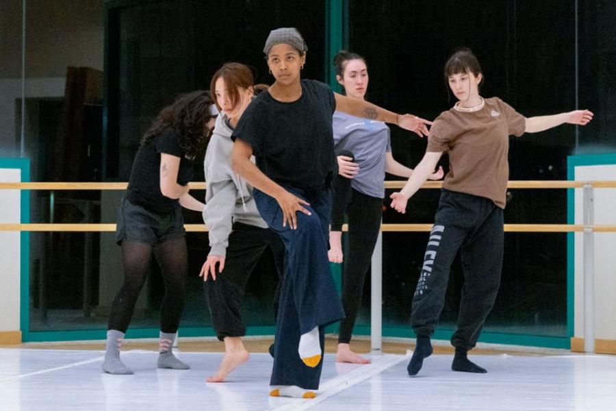 Five people perform a dance, creating a V formation with their bodies