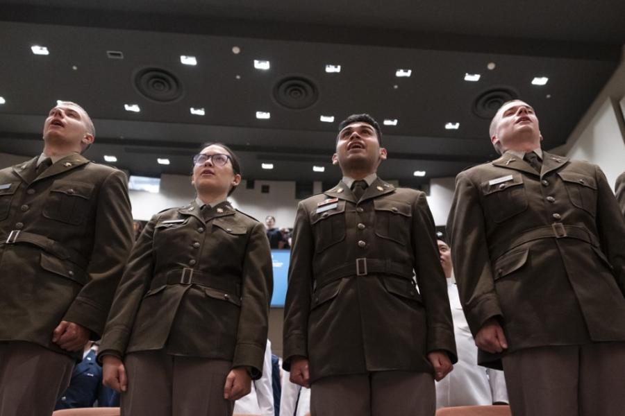 Five people in military uniforms stand at attention
