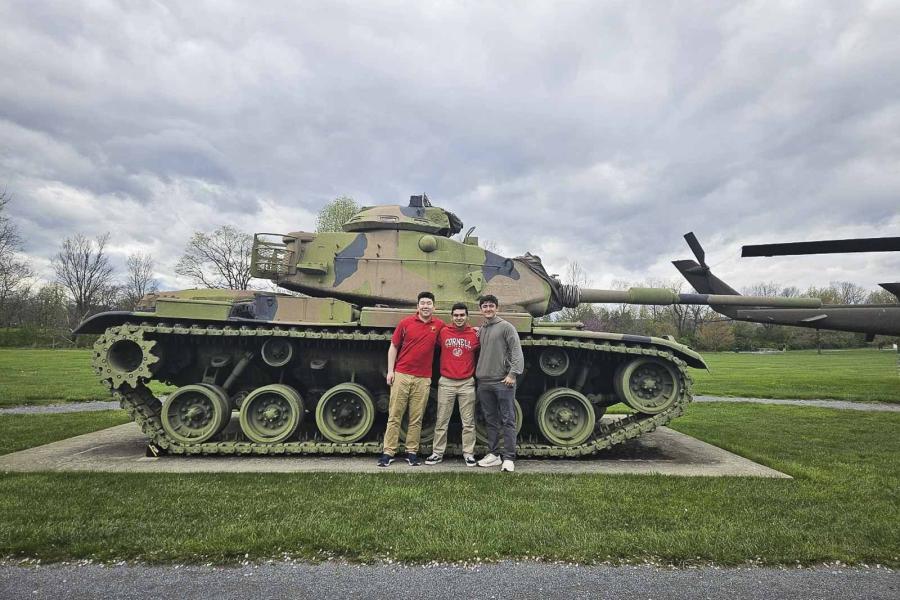 three people standing by a military tank
