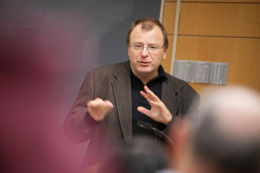Nicolas van de Walle speaking, hands moving, wearing glasses and a jacket