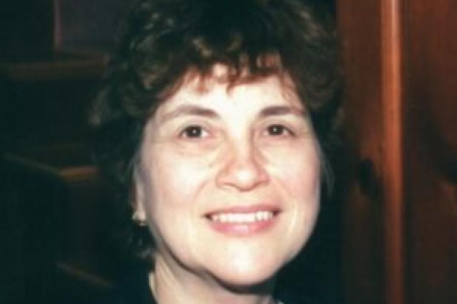 Deanne Gebell Gitner, smiling, with short black hair, a jacket and pearl necklace