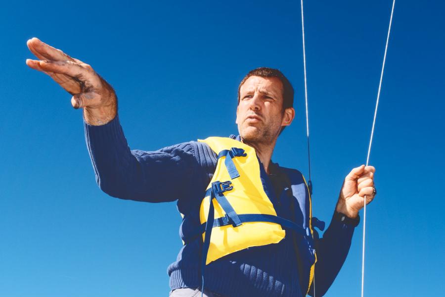 Person wearing a yellow life jacket, standing up in a boat