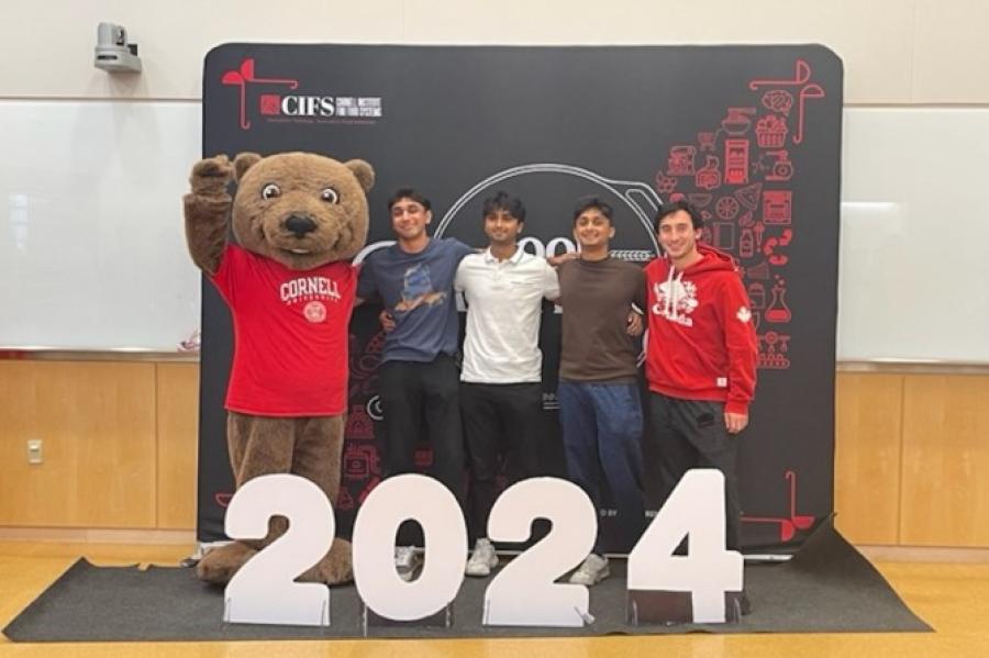 Four people stand with a mascot bear 