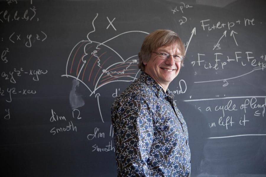 Michael Stillman, professor of mathematics, in front of a blackboard.
