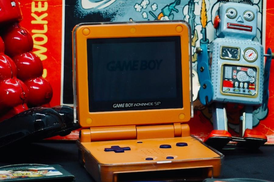 small orange handheld video game player with a spaceship backdrop