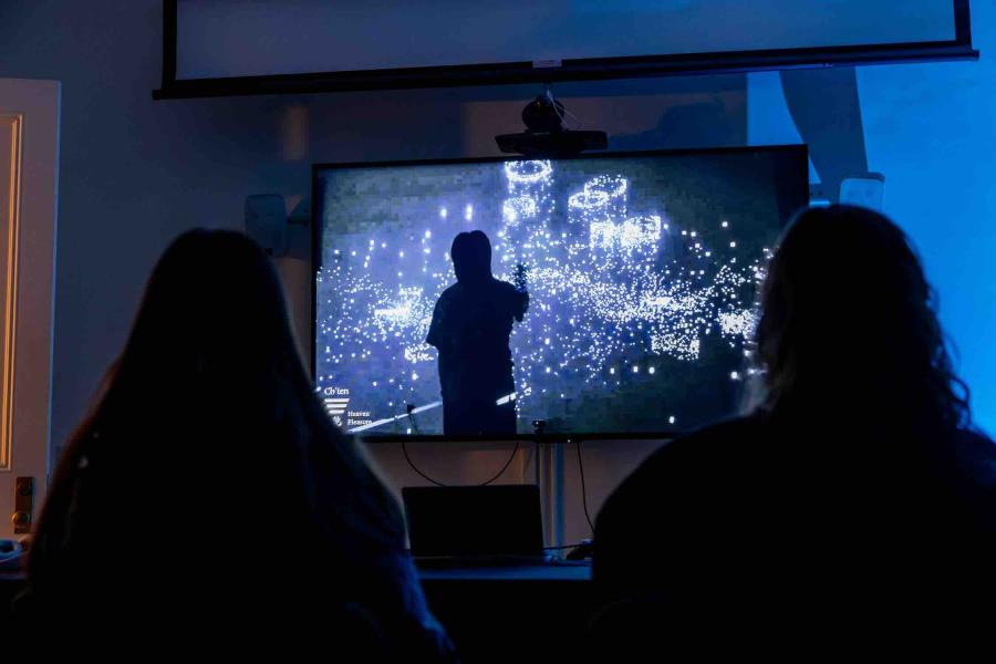 people watching projection on screen that looks like stars