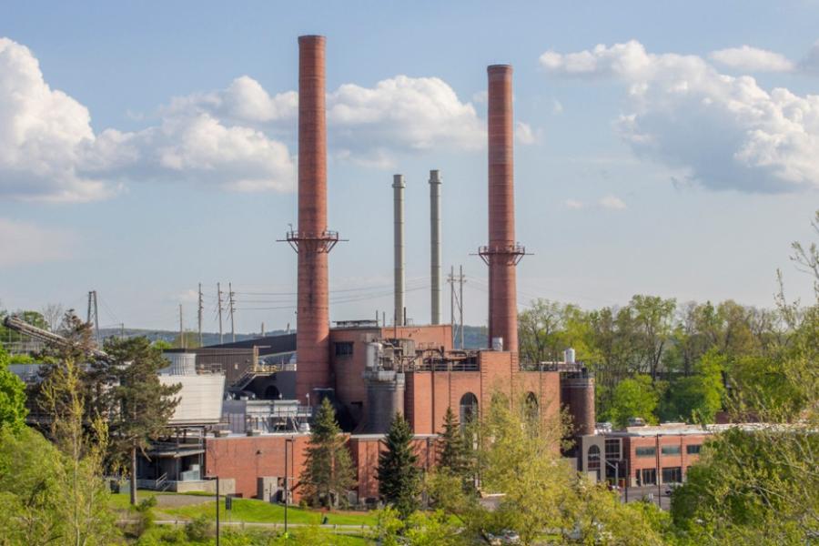 large brick building with smoke stacks reaching into a blue sky studded with clouds