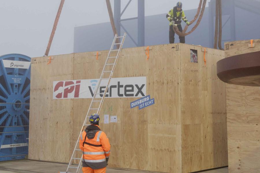 Man standing on top of huge crate attaching a cable to it.