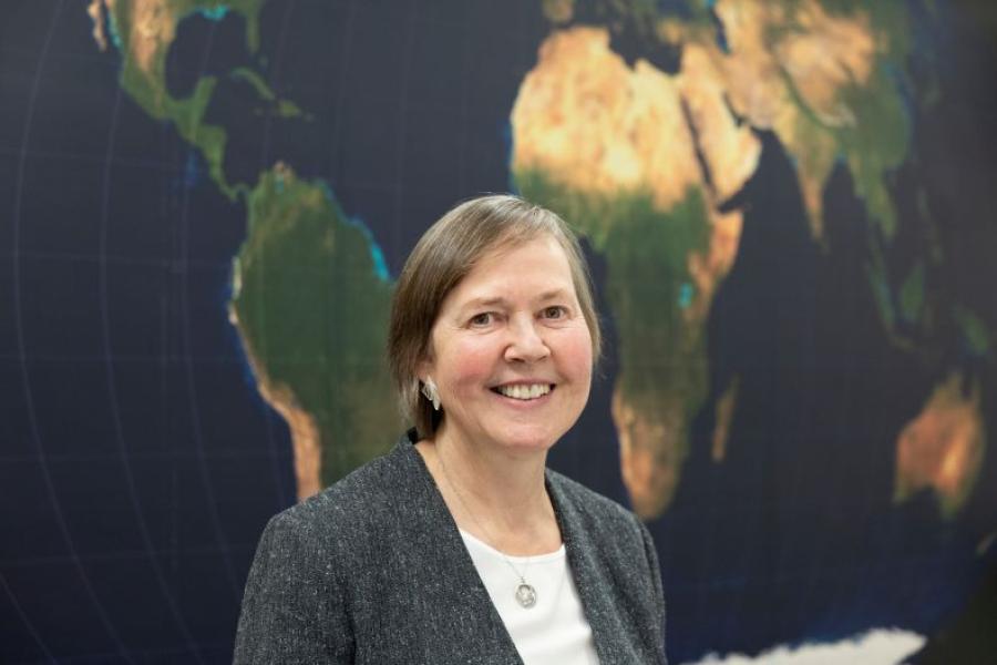 Ellen Lust, smiling, standing in front of a map of Africa