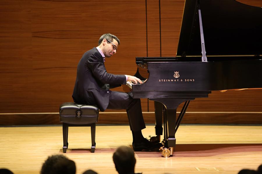 Person sitting at a grand piano, playing thoughtfully