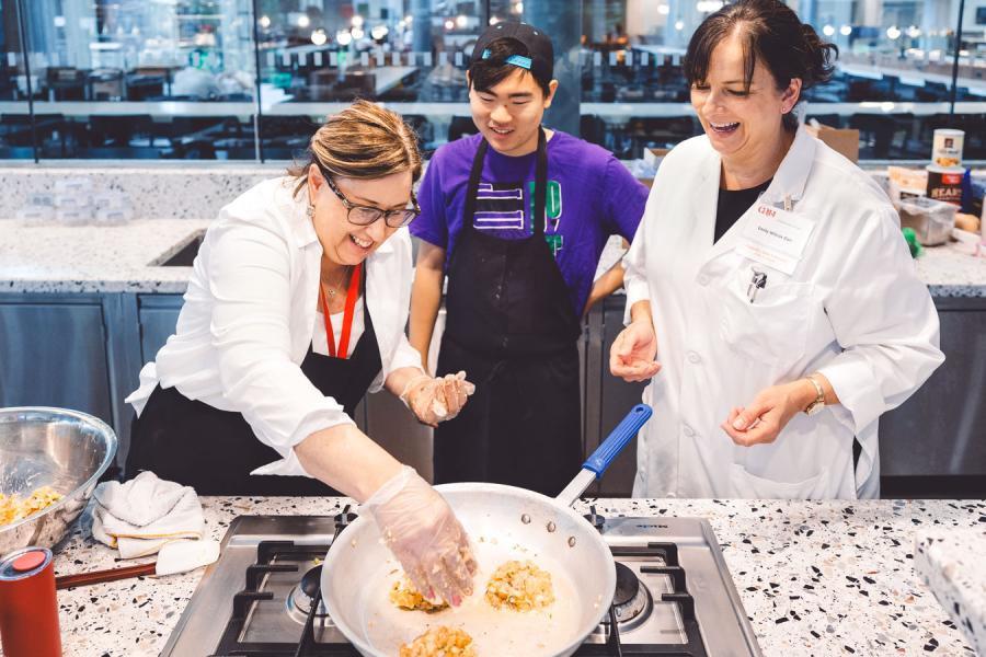 three people cooking over a stove