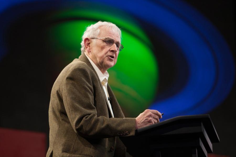 Person speaking at a podium with an image of a planet in the background