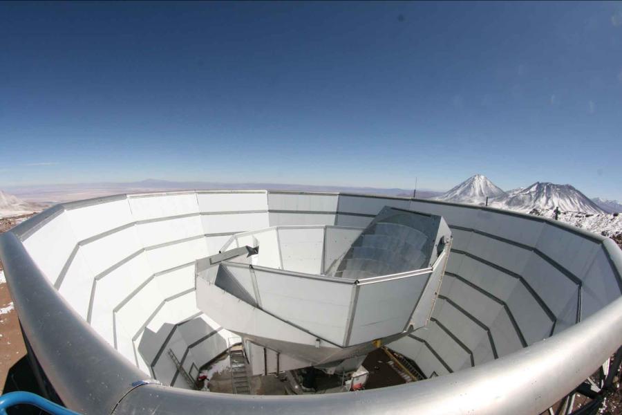 The multi-sided metal telescope with a smaller metal section in the middle and snow-capped mountains in the background.