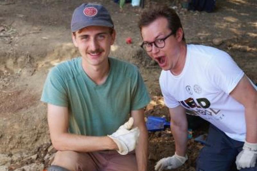 Two people kneel in the dirt