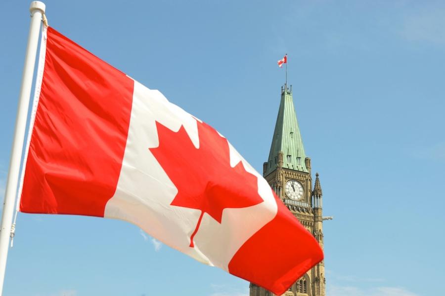 Canada's red and white flag with Ottawa's Peace Tower in the background