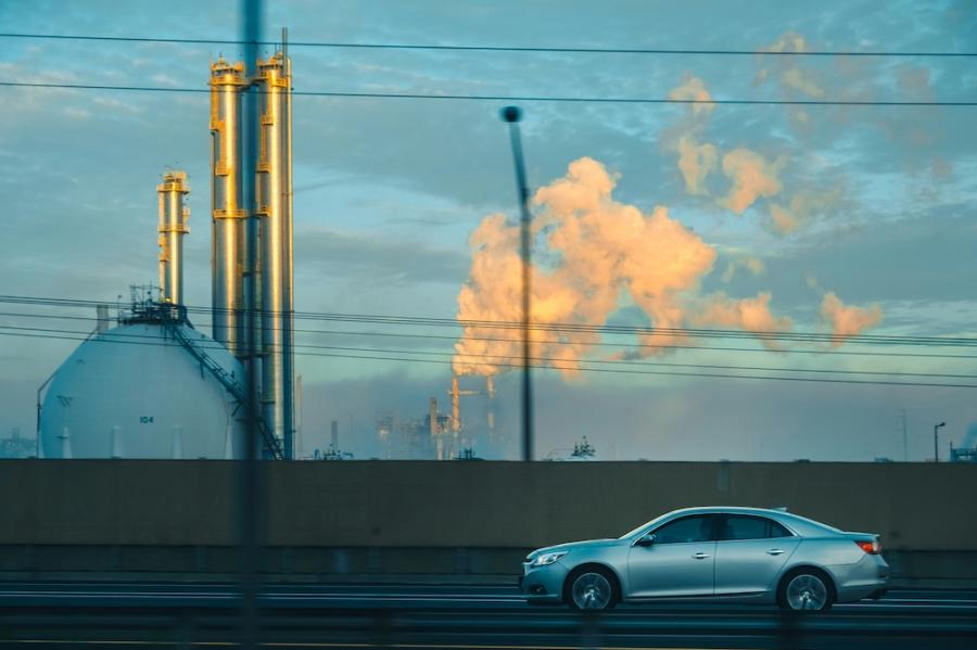 Car driving past a factory belching smoke