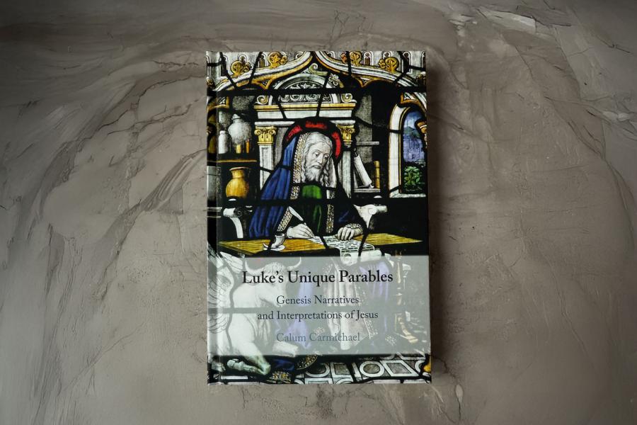 Image of aMedieval scholar sitting at a table writing with a quill pen