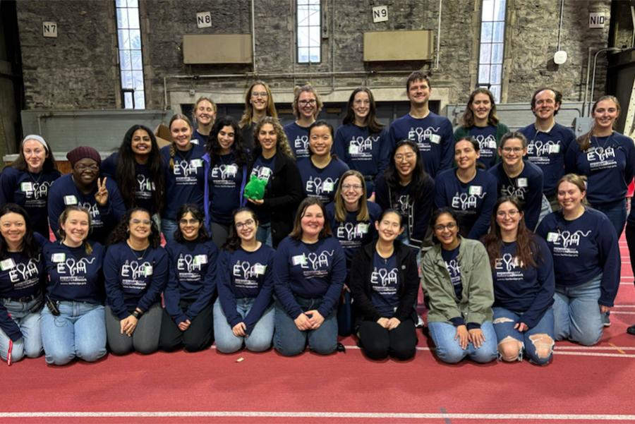 Several people standing in three rows, wearing dark blue shirts