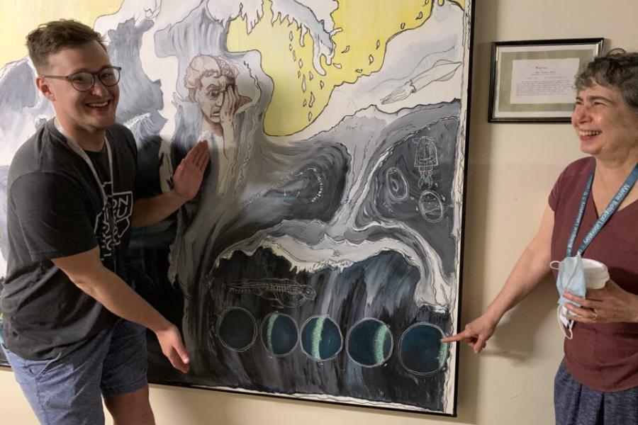 Two people laughing near a large poster showing a wave