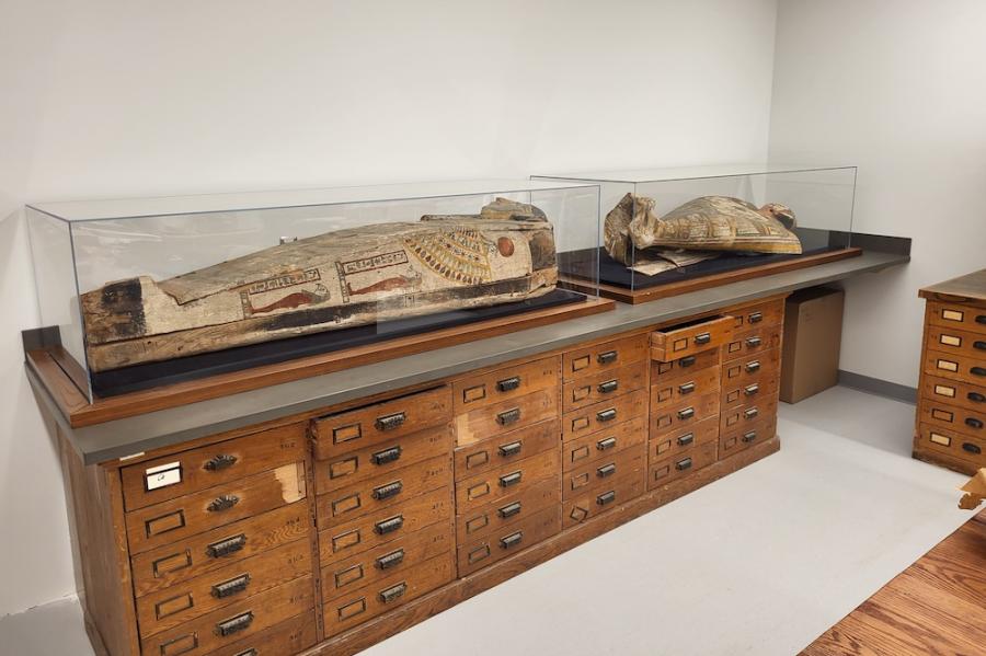 Two mummy cases on top of a large cabinet