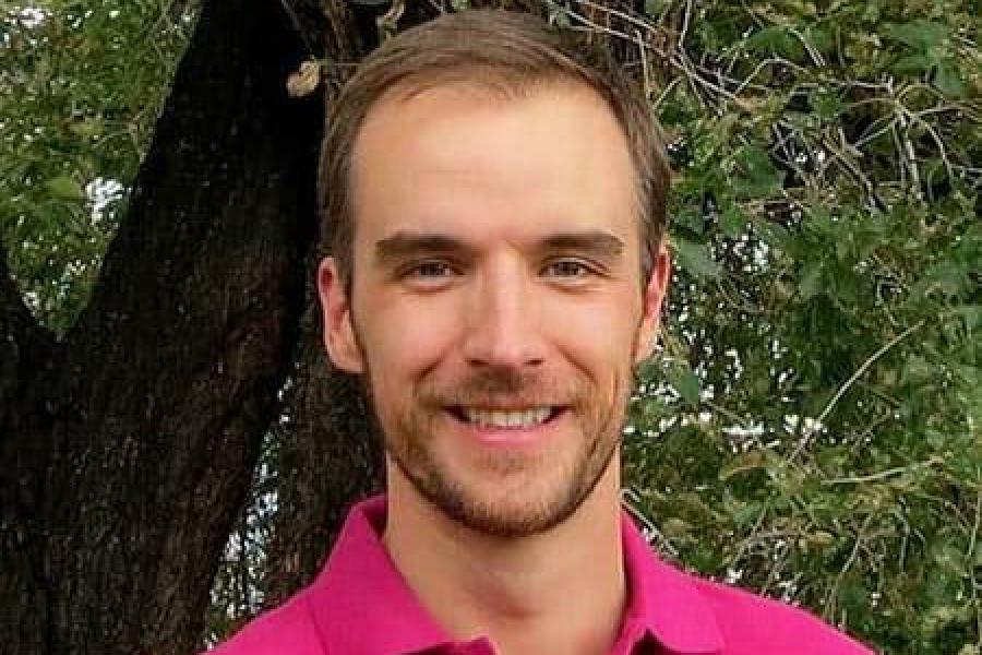 Brad Ramshaw, smiling, with very short mustache and beard, in a polo shirt in front of a tree