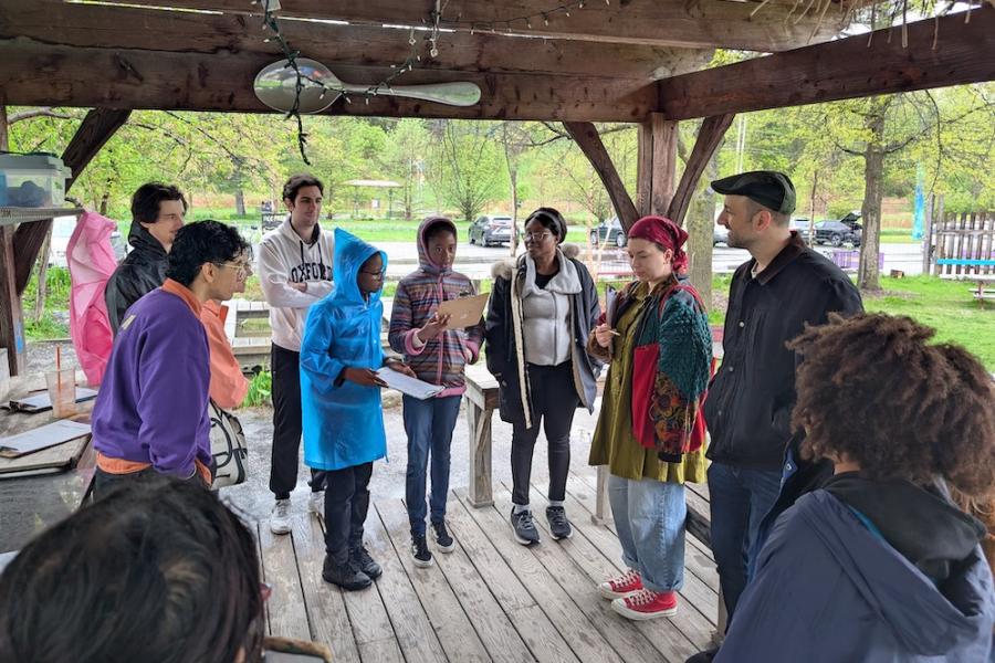Poetry reading Several people standing in a wood pavilion