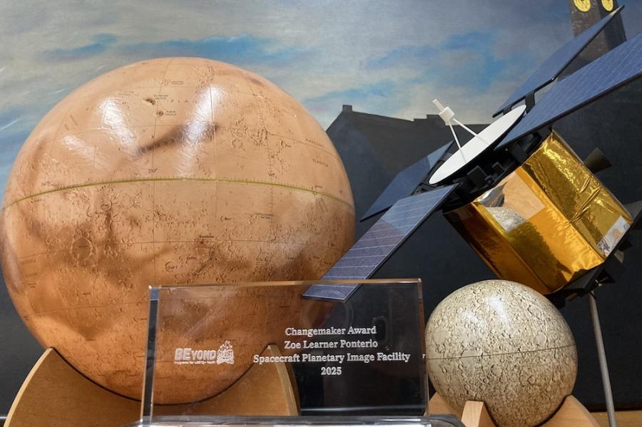 Rectangular glass award set among model planets on a table