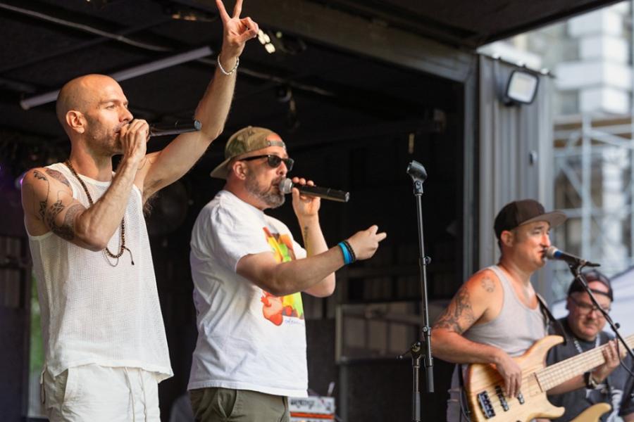three people singing from a stage