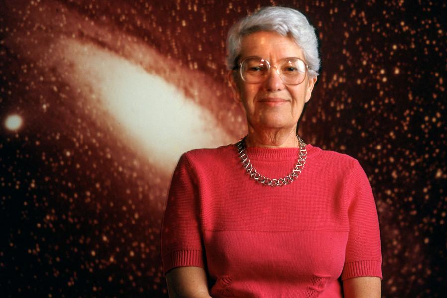 Person wearing red sits for a portait, backed by an image of a galaxy